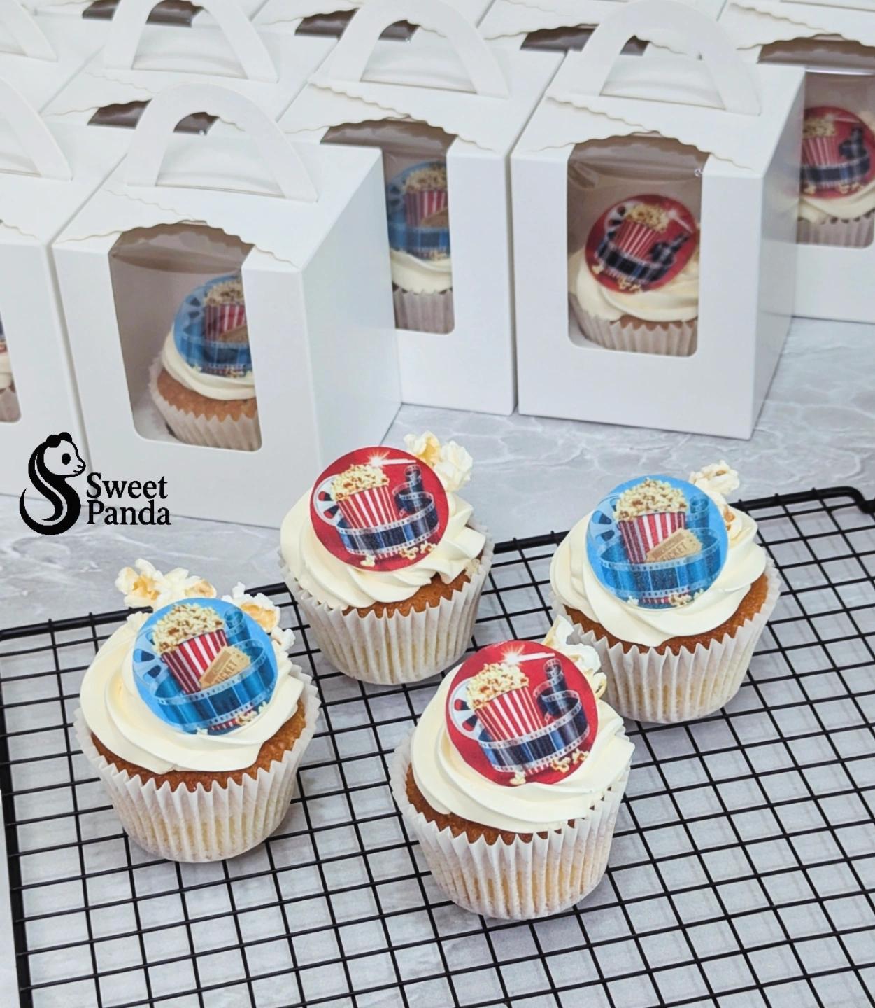Four vanilla cupcakes with white buttercream frosting topped with red and blue circular printed images featuring a tartan