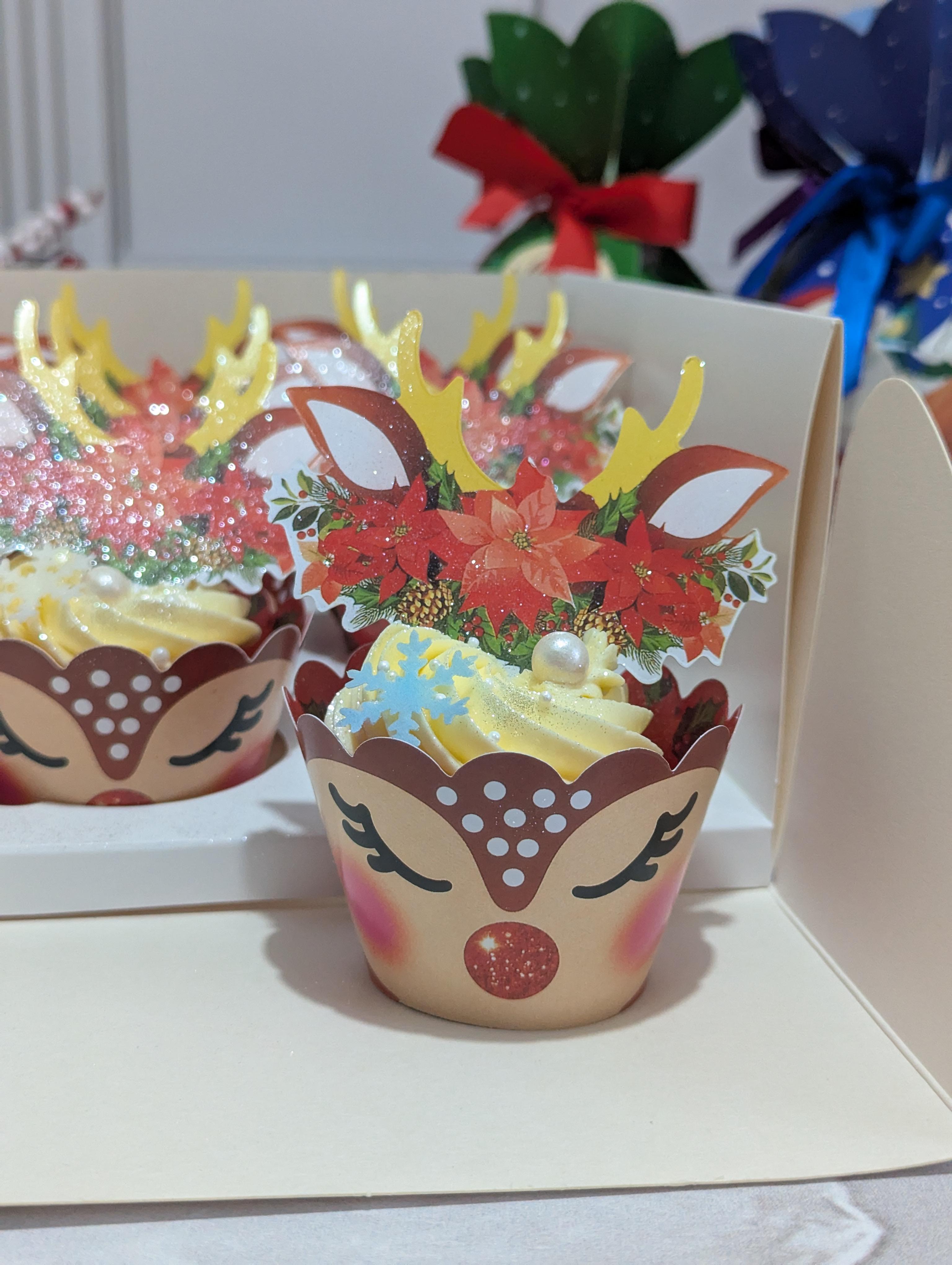 Christmas vanilla cupcakes decorated with reindeer face wrappers featuring yellow antlers, red noses