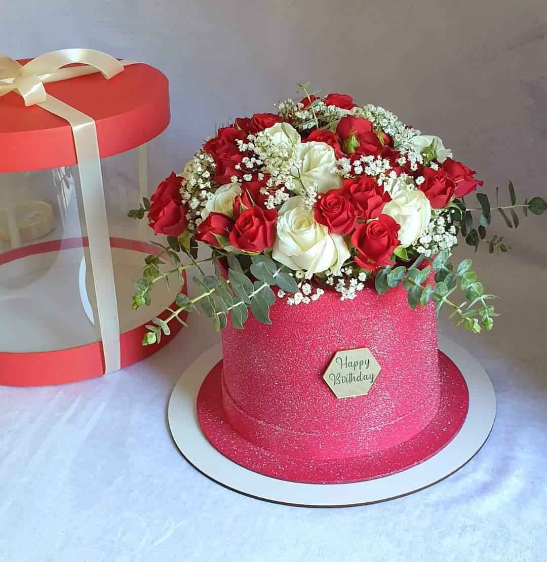 Pink glitter fondant cake topped with red and white roses, baby's breath, eucalyptus foliage and a 'Happy Birthday' plaque