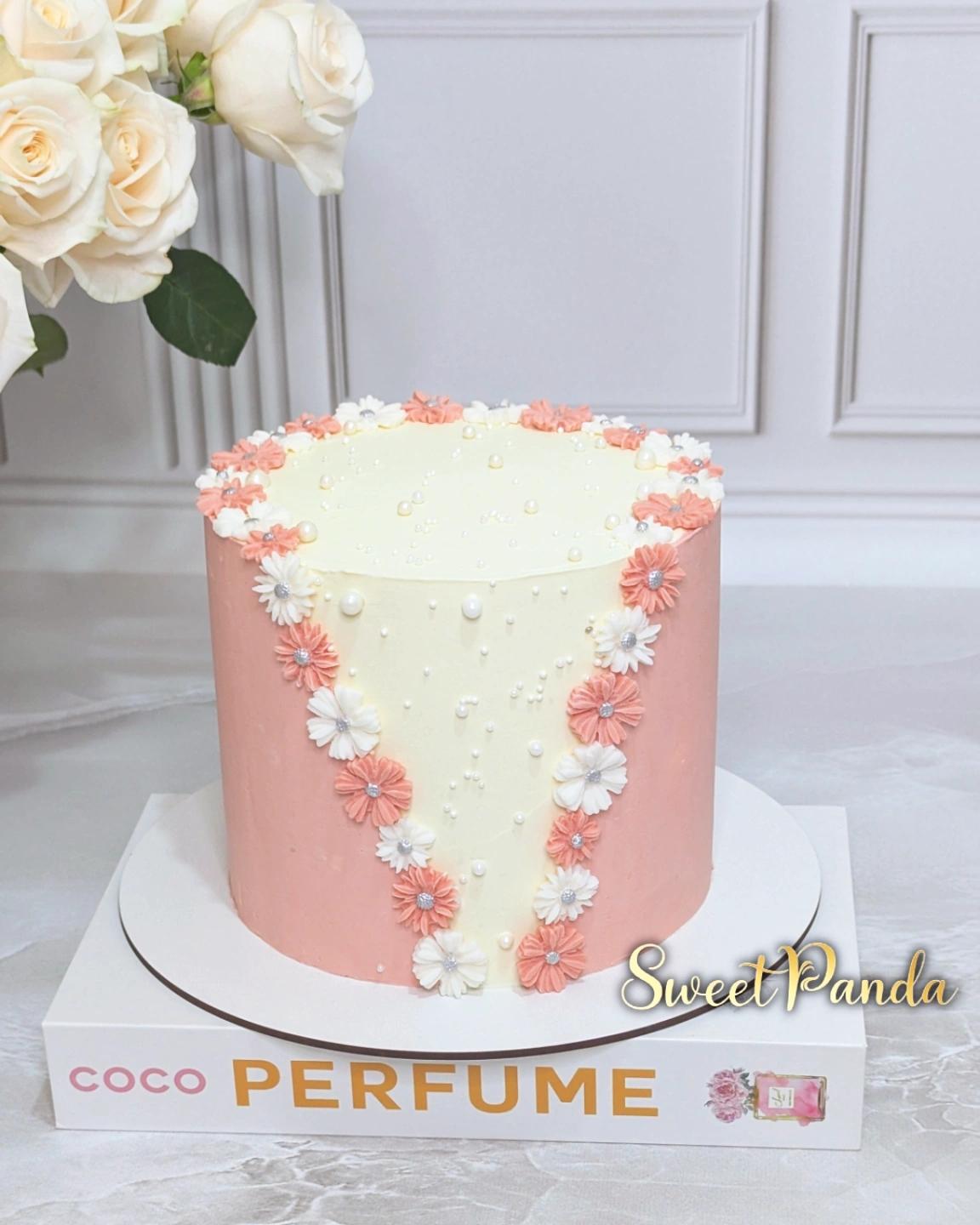 Single-tier cake with pink buttercream base and cream top