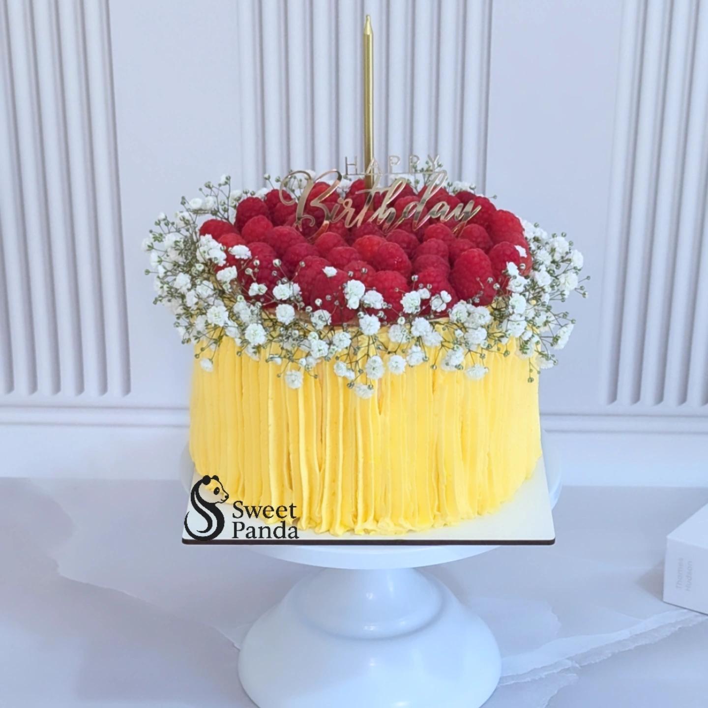 Single-tier birthday cake with yellow ruffled buttercream sides, topped with red roses, white gypsophila