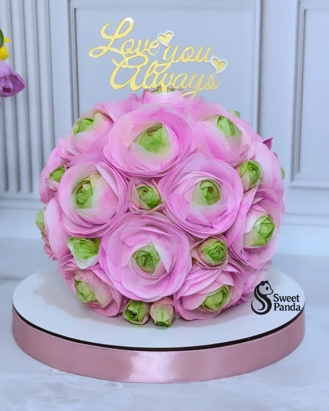 Pink wafer ranunculus cake with green centres on white base, topped with gold 'Love you Always' topper