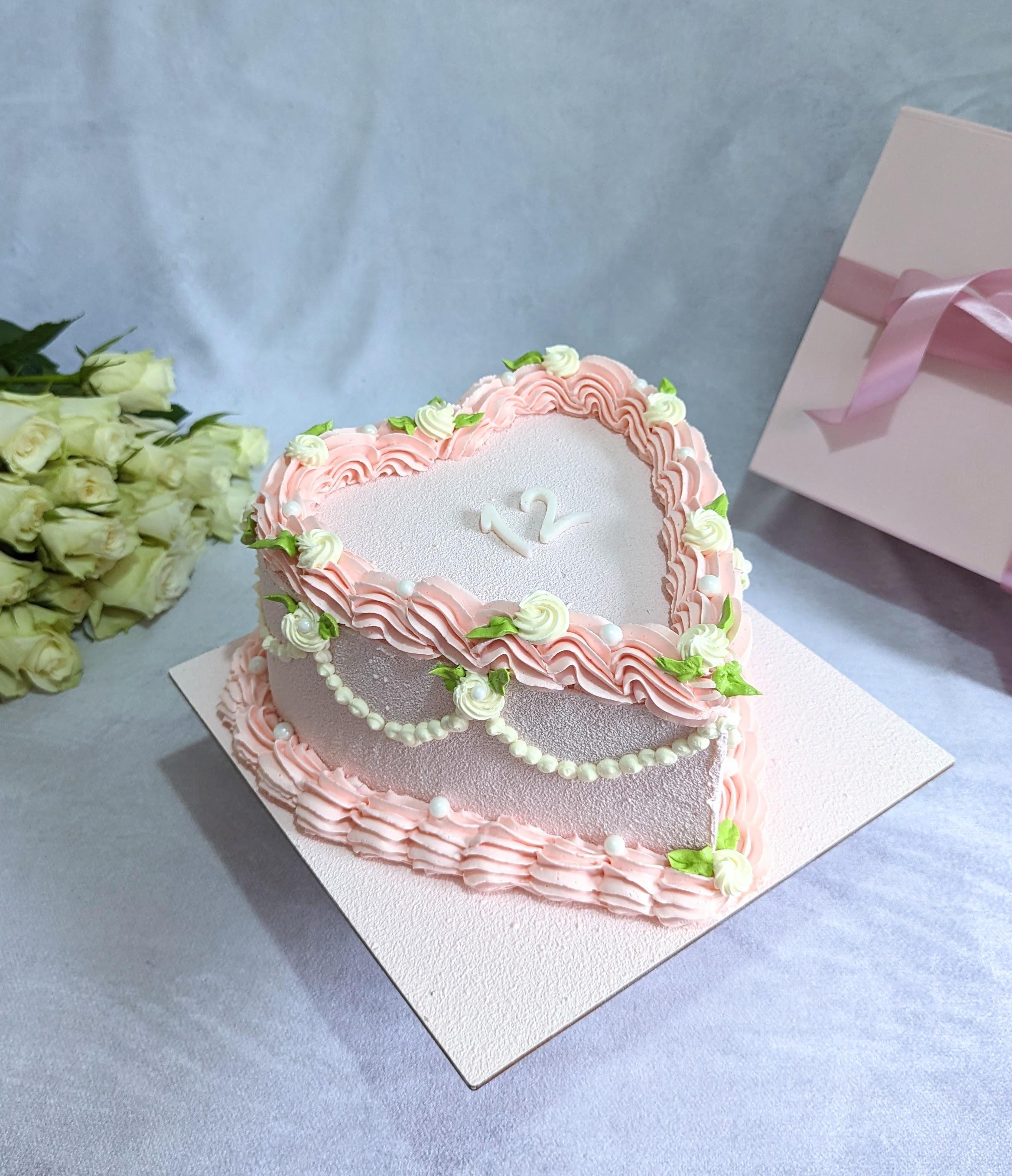 Two-tier celebration cake with pink and white textured buttercream piping, cream sugar flowers