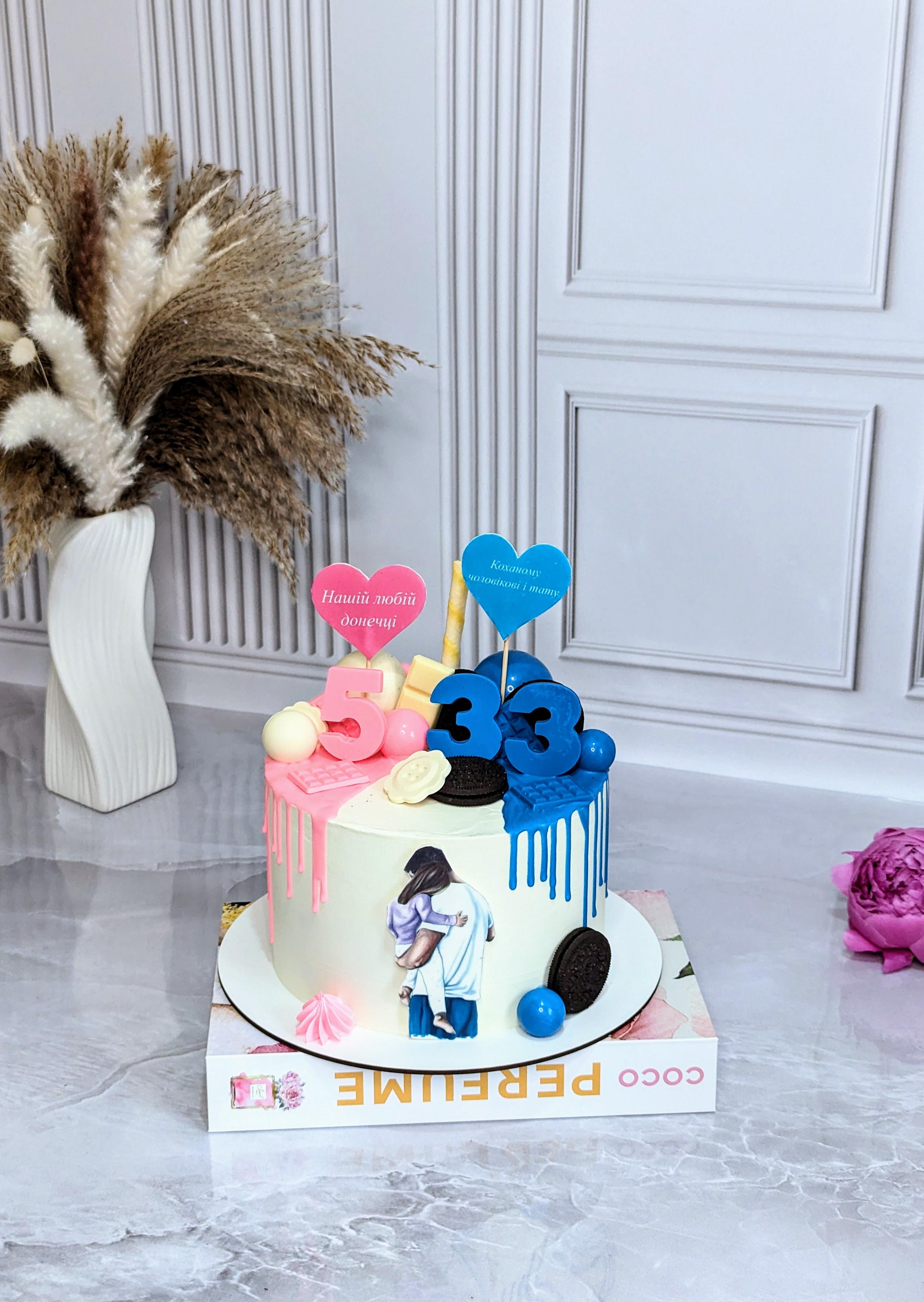 Two-tier celebration cake with pink and blue drip finish, decorated with number 33 toppers