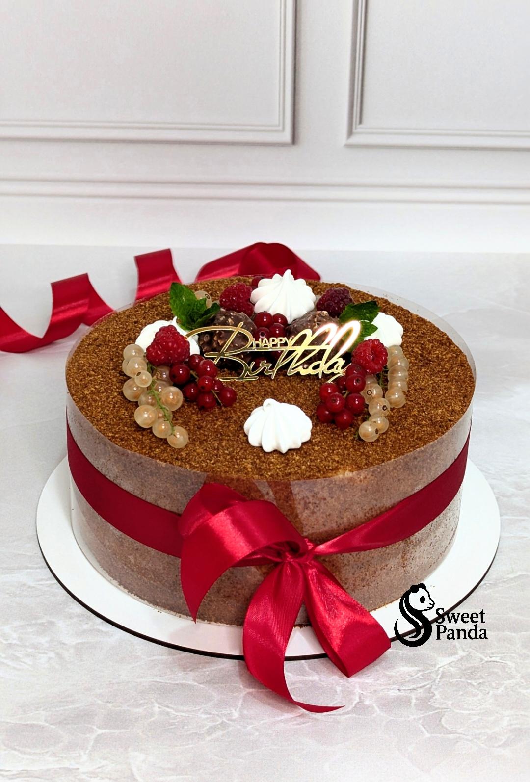 Two-tier honey cake with brown textured finish, decorated with fresh raspberries, redcurrants, white cream piping