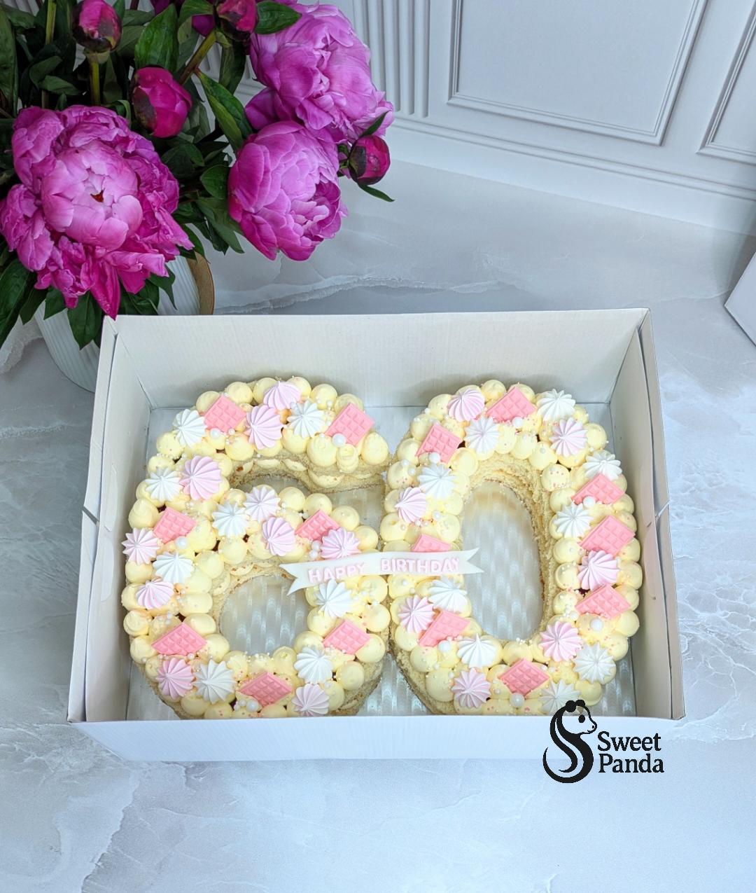 Number 50 celebration cake with pale yellow sponge, decorated with small piped meringues and pink and white wafer flowers