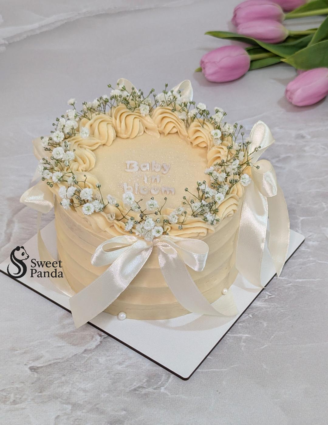 Cream textured buttercream cake decorated with piped peach swirls, baby's breath flowers, white wafer paper butterflies