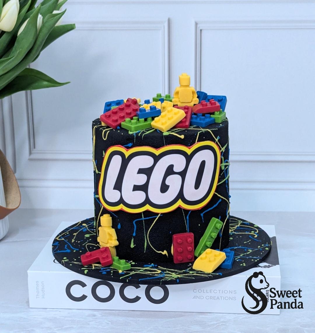 Two-tier black fondant cake with Lego logo and coloured Lego brick decorations on top and sides